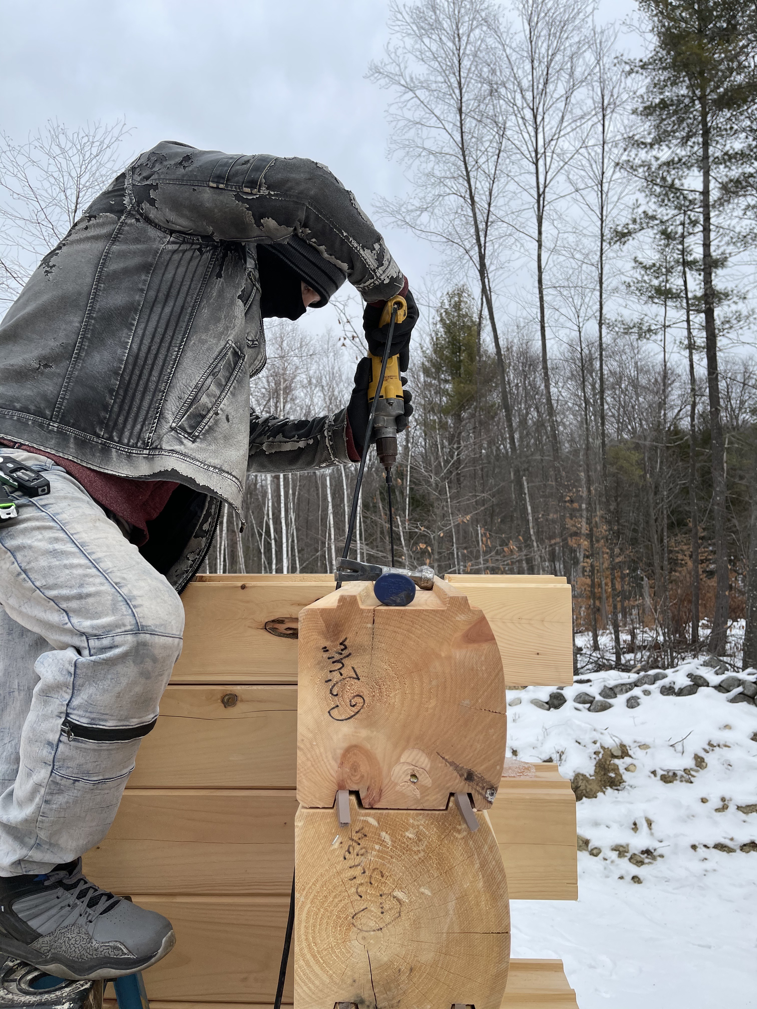 Builder fitting precut, labeled Merrimac log notches during winter build — Builder's Package log home assembly