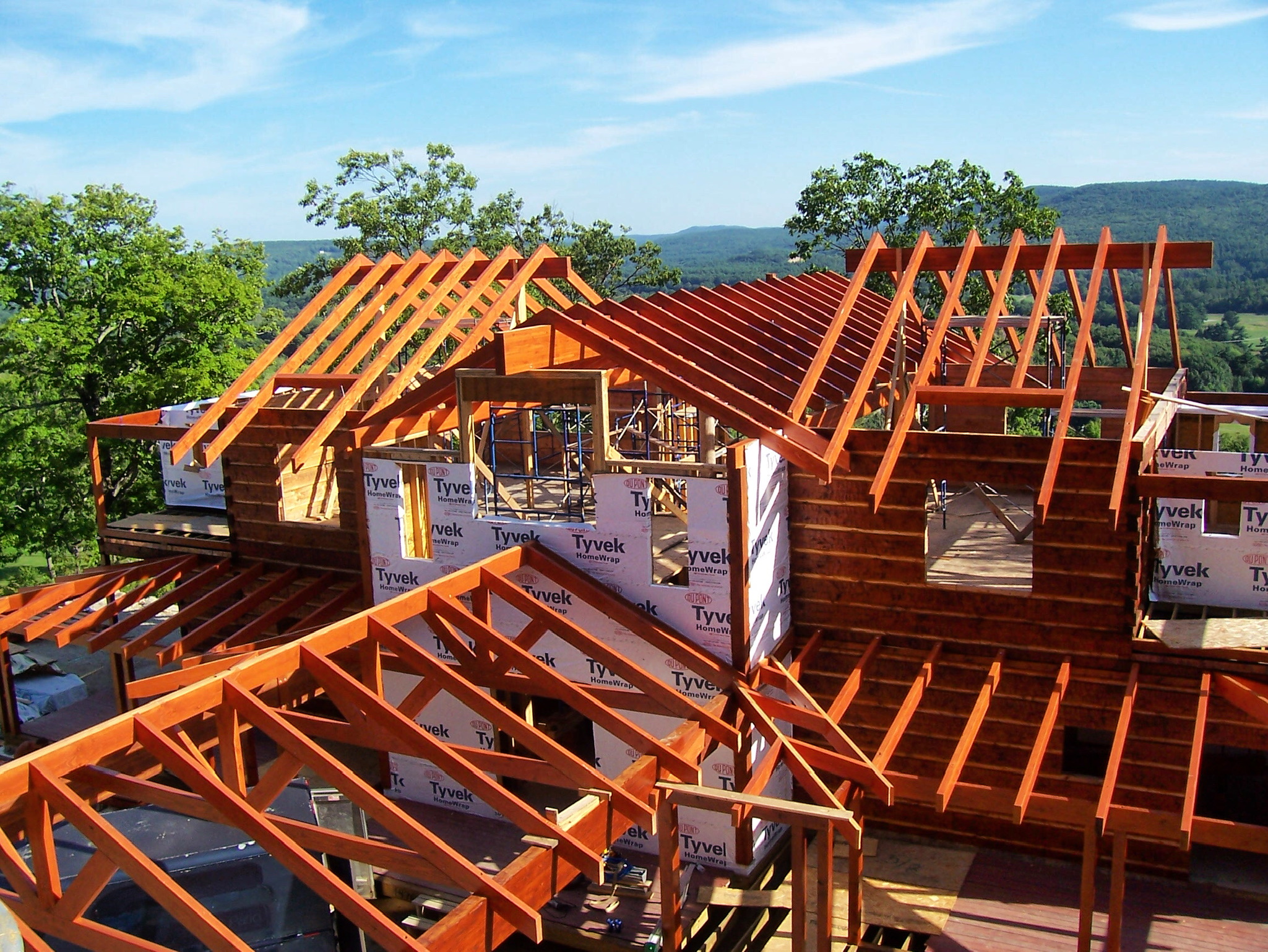 Custom Merrimac log home timber frame construction in progress with mountain views — modern post-and-beam build