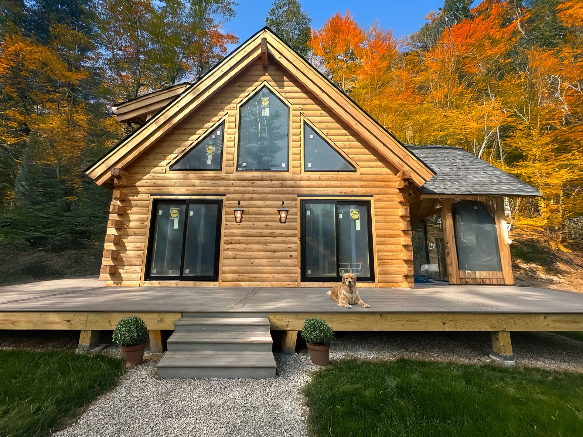 The Freedom log home with peak fall foliage and dog on the front deck