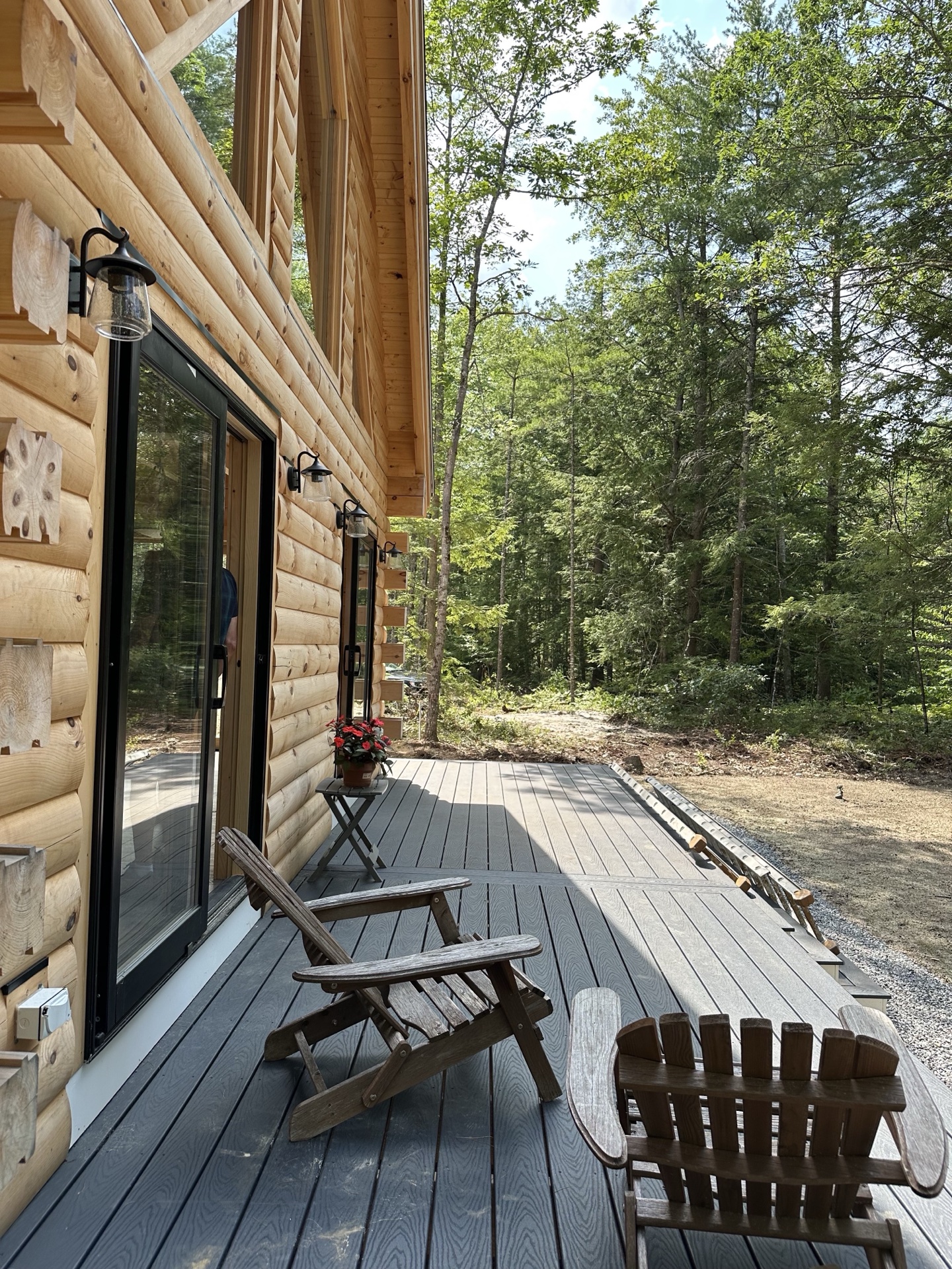 Side deck of the Freedom log home with adirondack chairs facing the woods