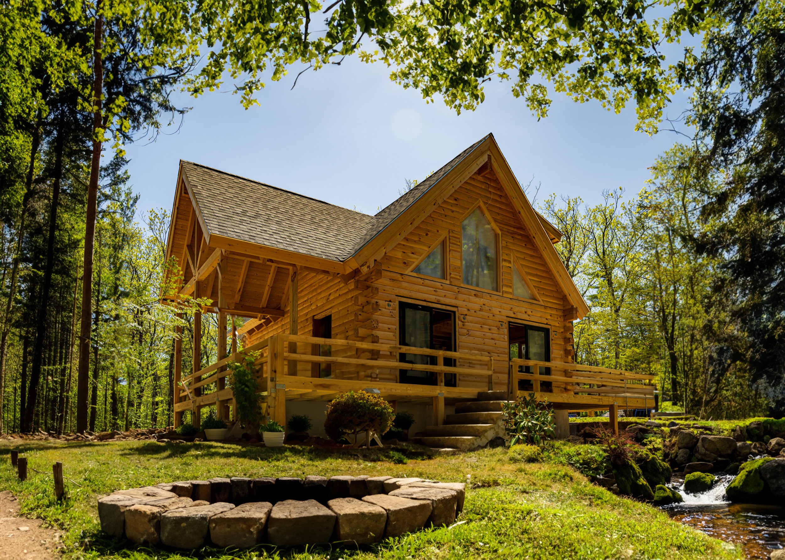 A richly stained Eastern White Pine log home glowing in full sunlight, the finish beading water and protecting the logs