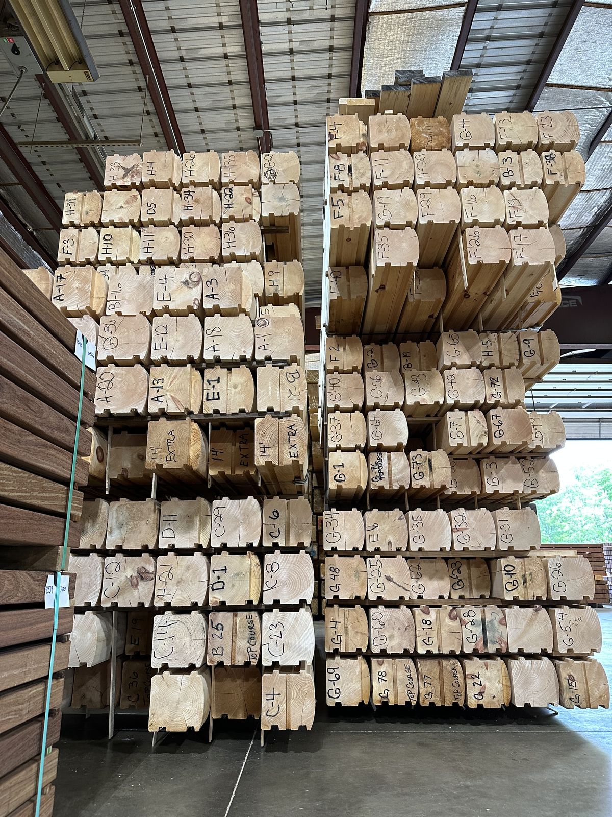 Racks of pre-cut Eastern White Pine log ends at the Merrimac mill, each course hand-lettered and numbered for its exact place in the build
