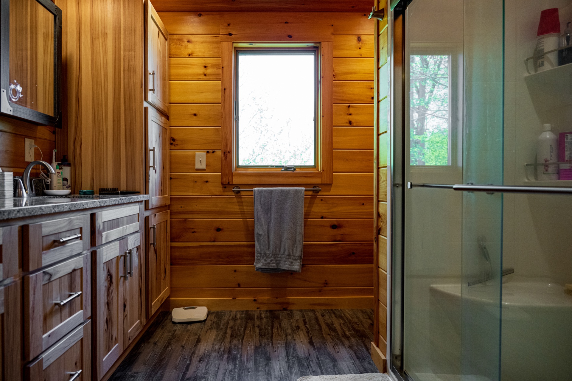 Ossipee bathroom with glass-door shower, granite vanity, and pine accent wall with window
