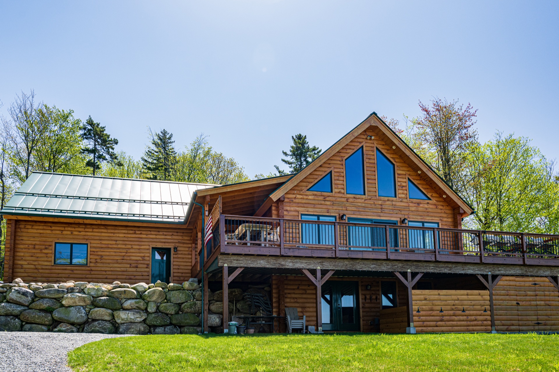 The Ossipee log home front elevation with cathedral windows, deck, and walk-out lower level