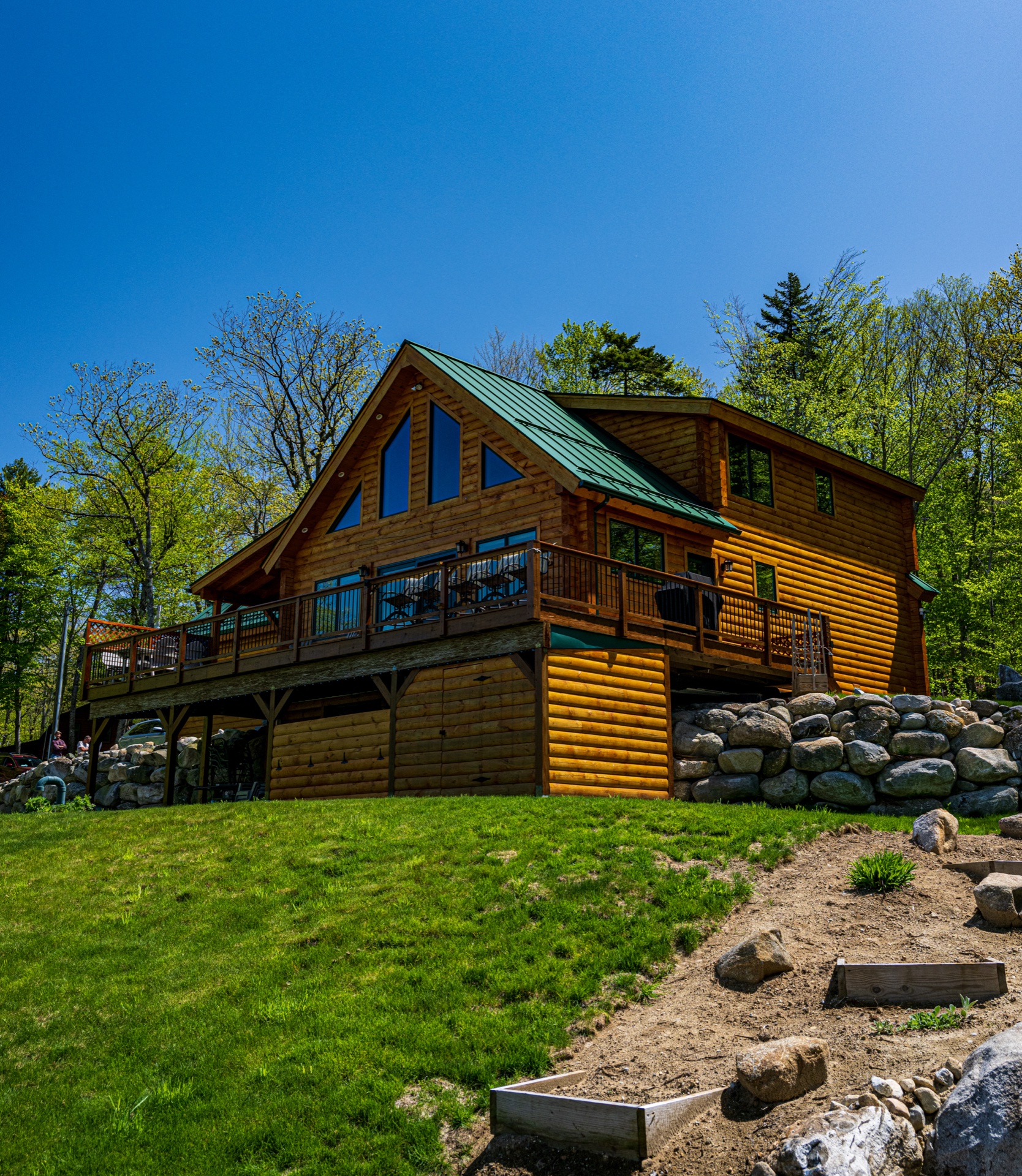 The Ossipee log home rear three-quarter view with walk-out basement and stone landscaping