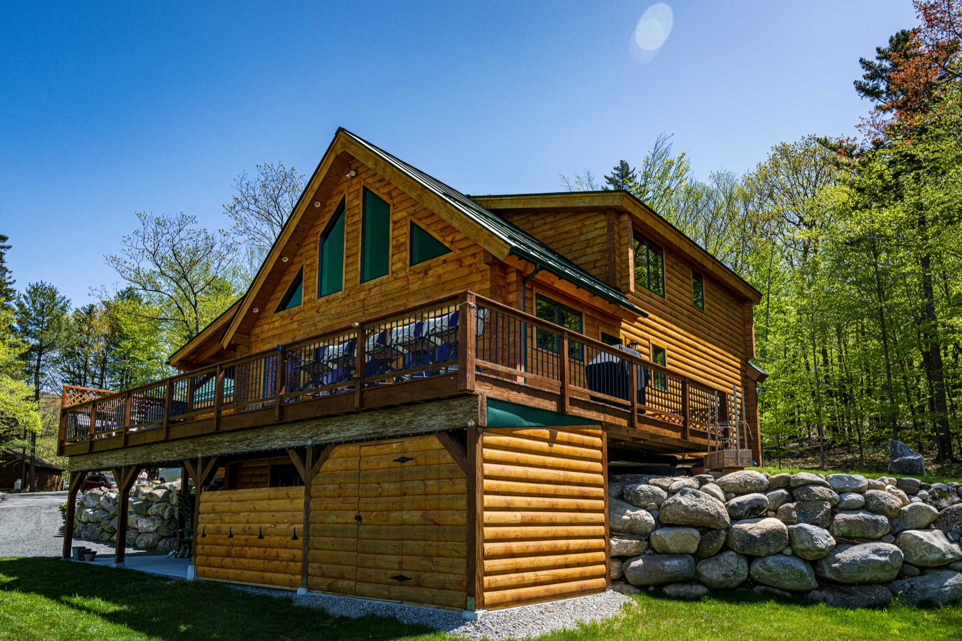 The Ossipee log home side angle showing elevated deck and walk-out garage doors