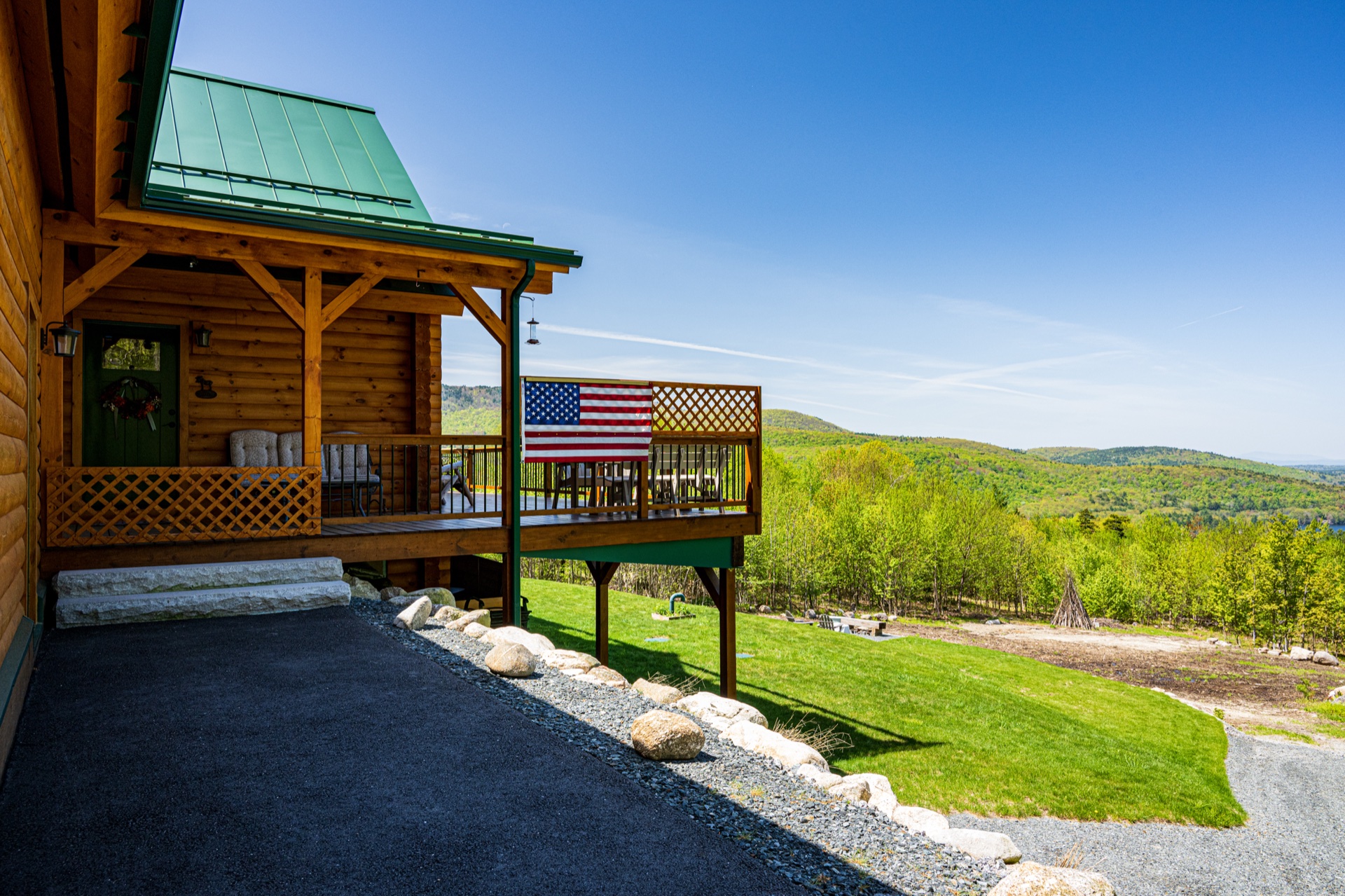 The Ossipee log home front porch with American flag and mountain view