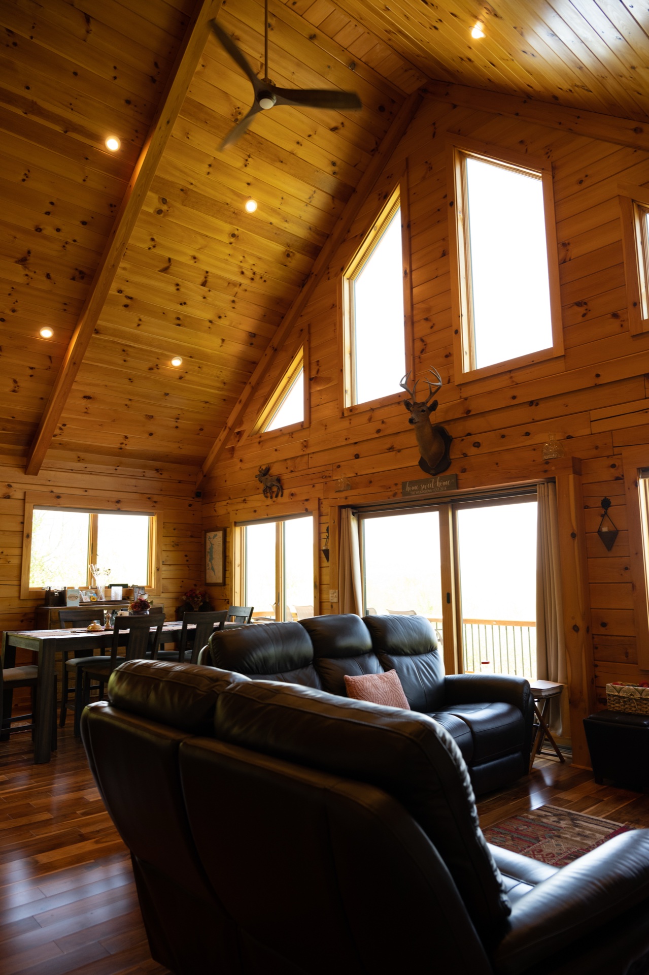 Ossipee great room with two leather recliner couches, cathedral ceiling, ceiling fan, and deer mount