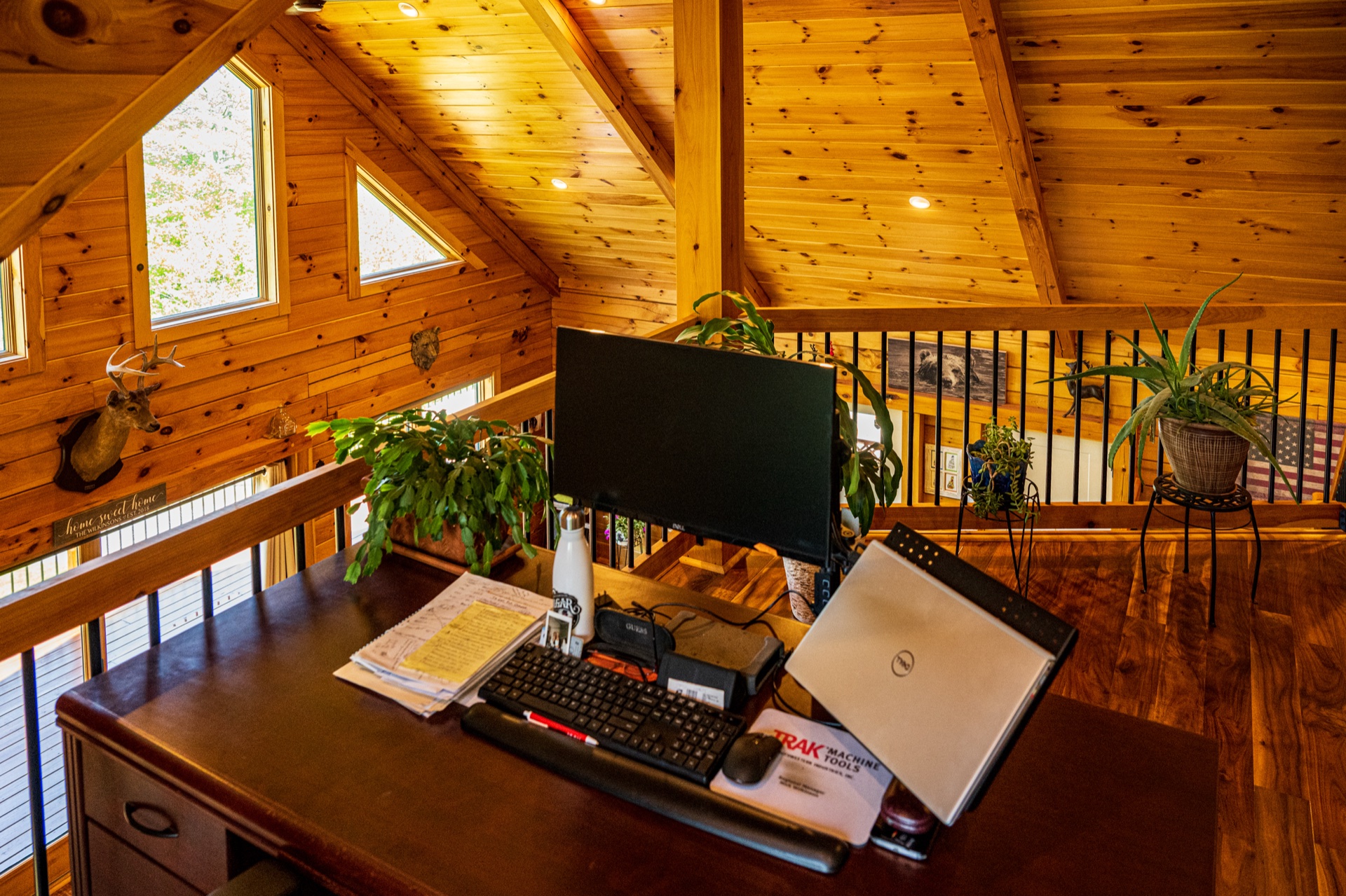 Ossipee loft office desk closeup with computer, laptop, and houseplants overlooking the great room