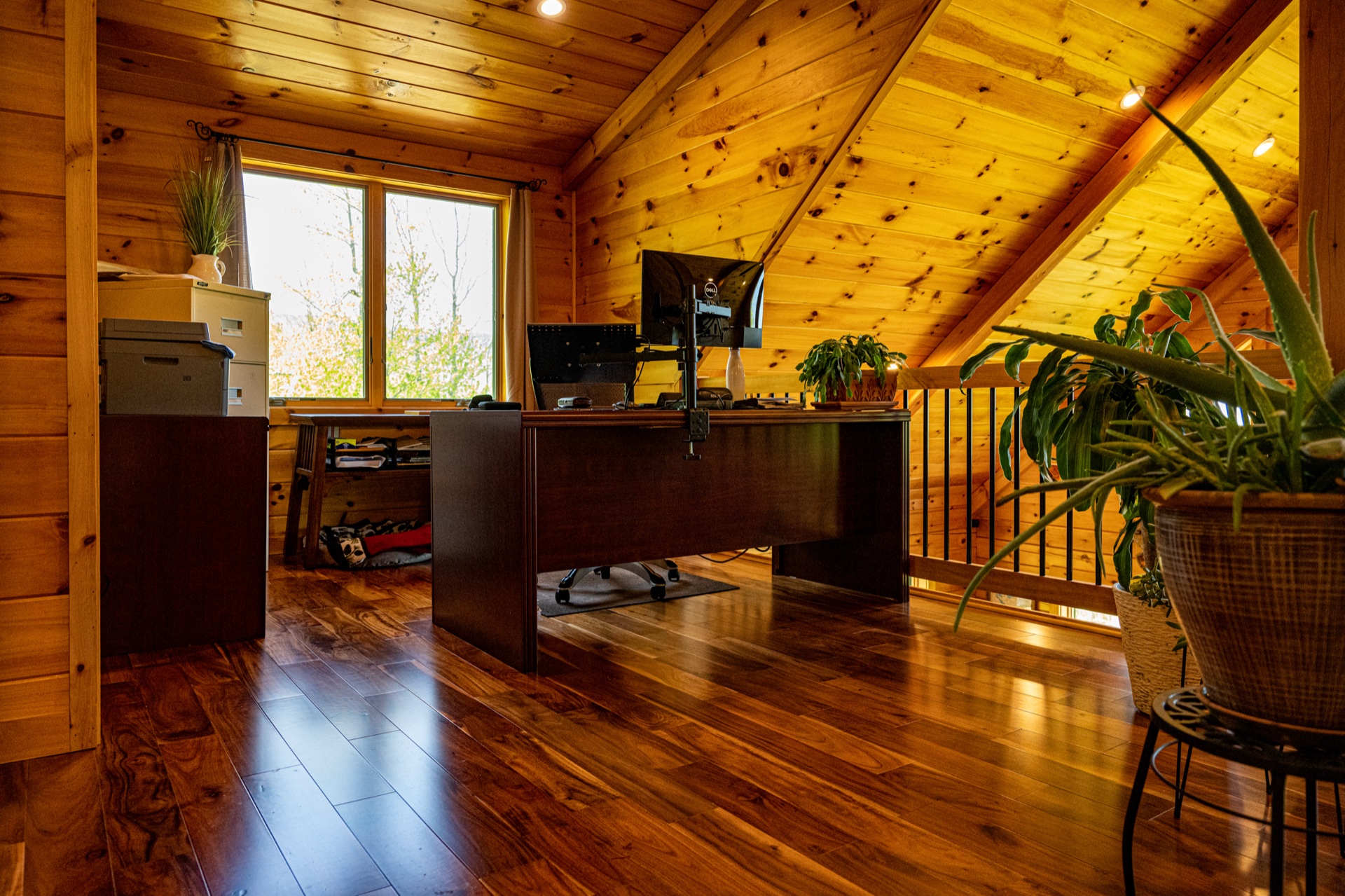 Ossipee loft home office with desk, plants, and sloped pine ceiling