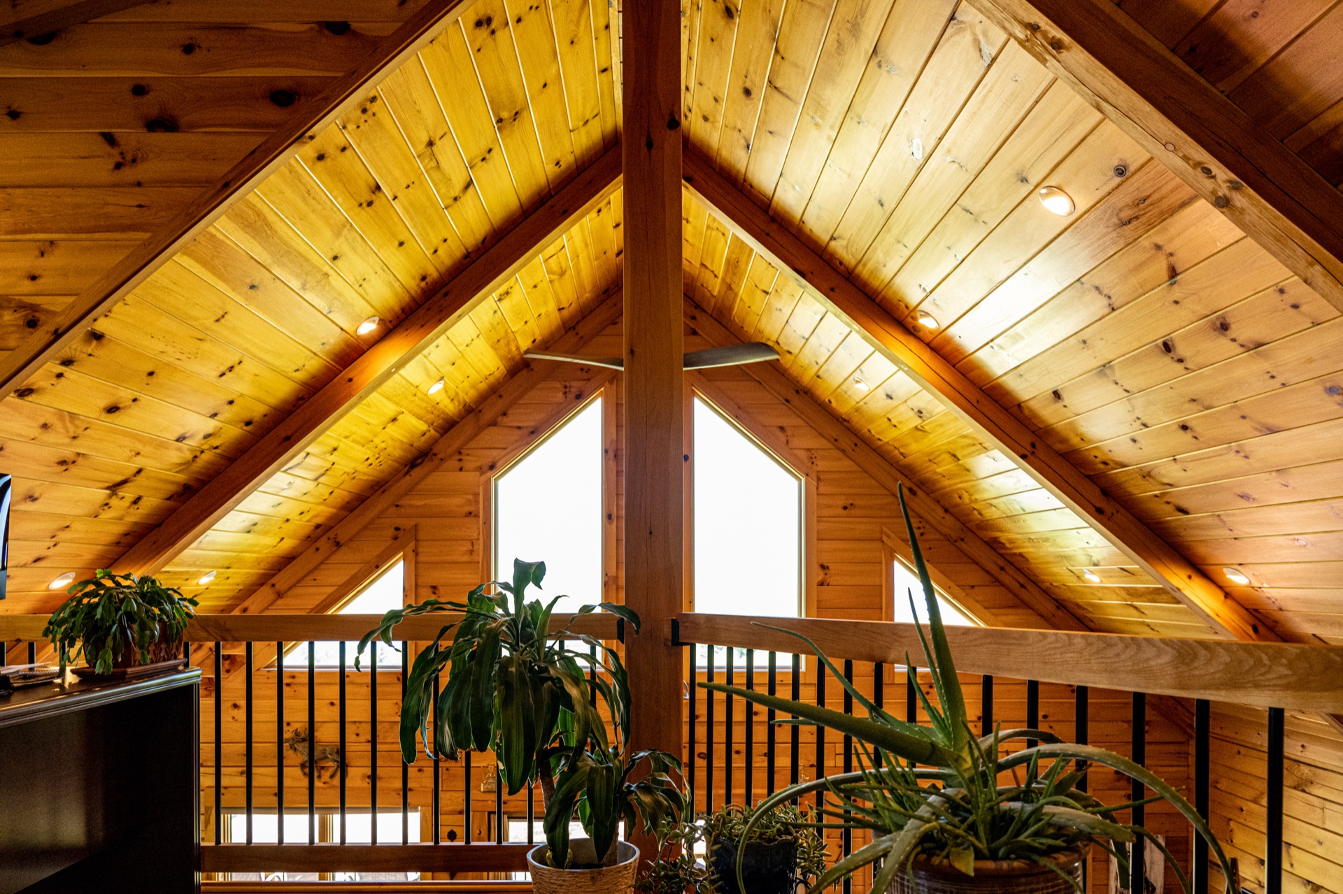 Ossipee loft with vaulted A-frame ceiling, triangular windows, and exposed beams