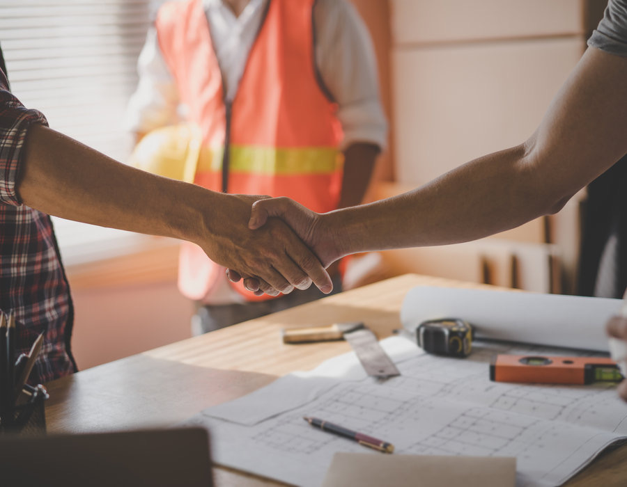 A handshake over blueprints, representing the direct communication between Merrimac's mill and the homeowners and builders who buy straight from the source