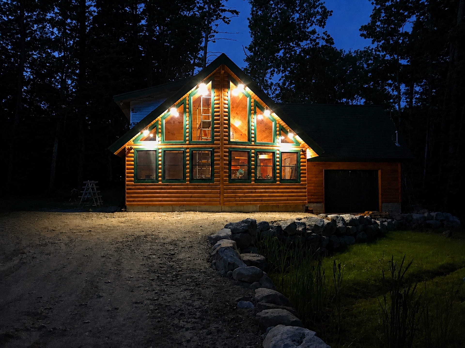 The Silver Lake log home at night with string lights illuminating the prow windows