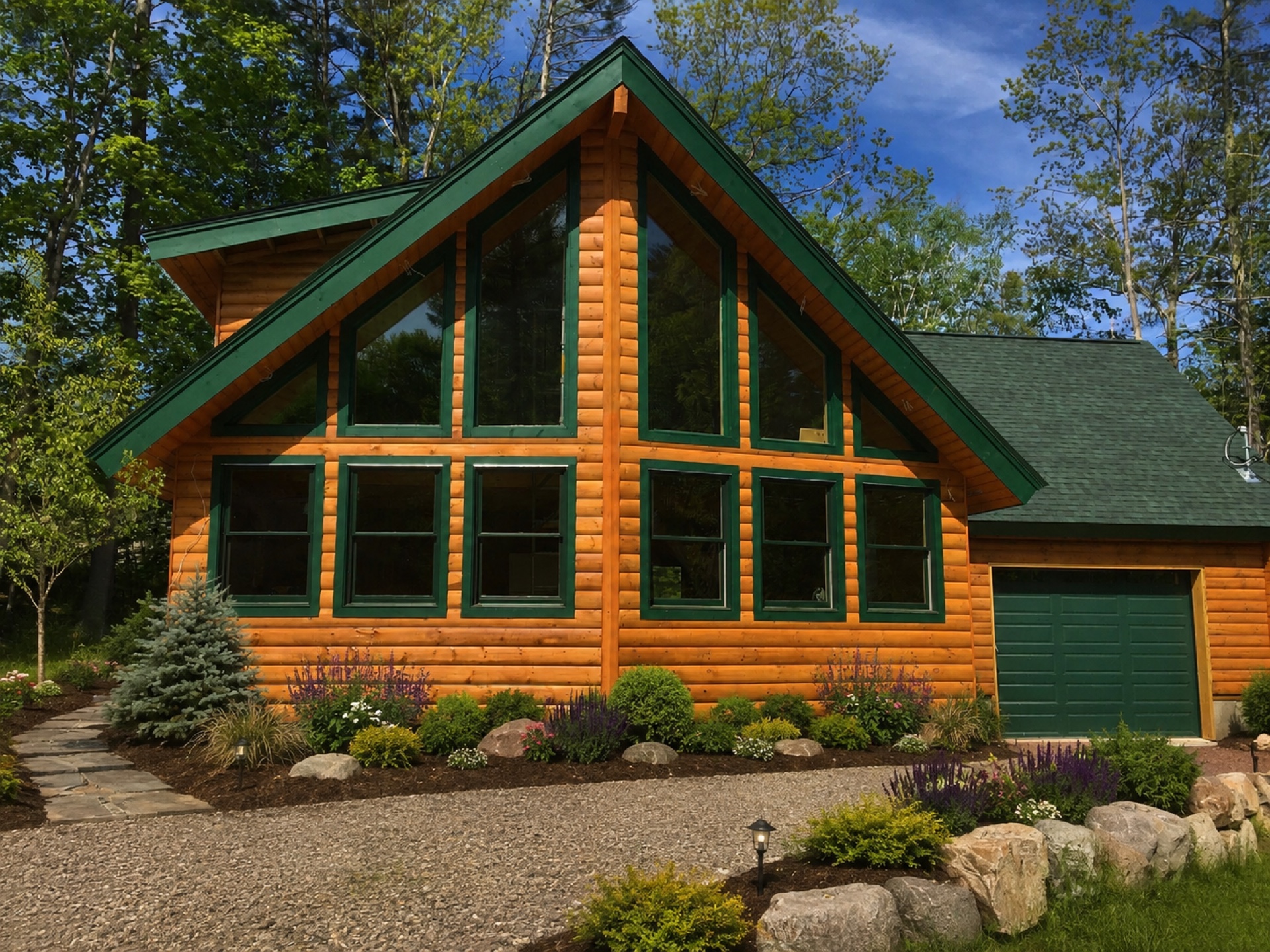 The Silver Lake prow log home with floor-to-ceiling windows, cathedral ceiling, and attached garage in a forested setting