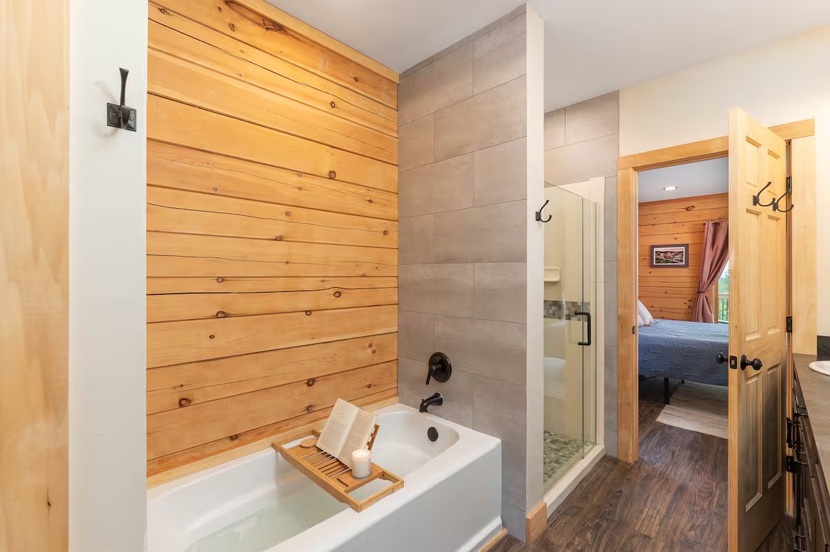 Sunapee bathroom with soaking tub, pine accent wall, and view through to the bedroom