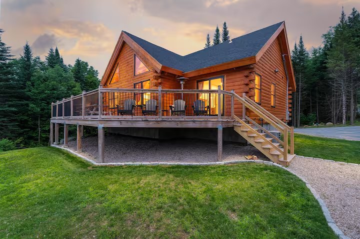 Sunapee log home exterior at dusk with warm interior lights glowing through the windows
