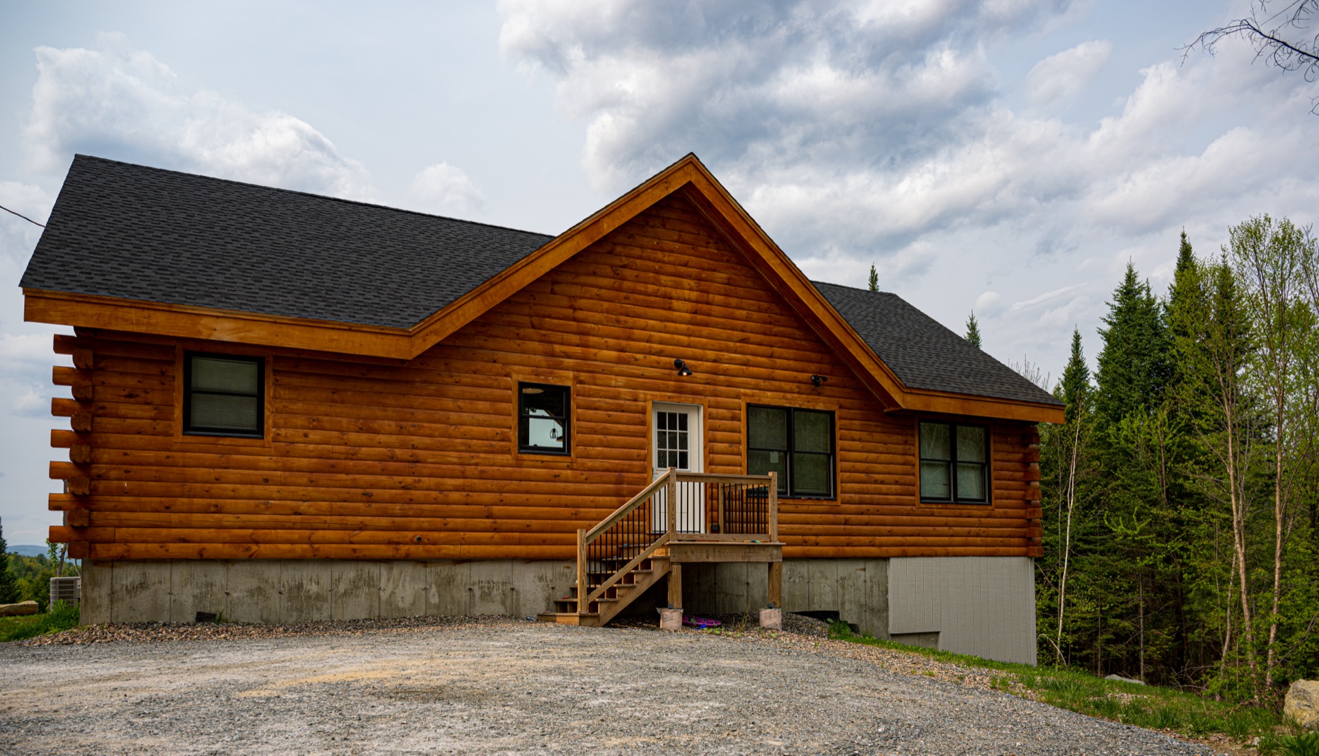Front exterior of the Sunapee log home with entry steps and Eastern White Pine logs