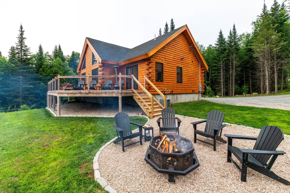 Sunapee log home with fire pit and adirondack chairs in summer, deck and walkout basement visible