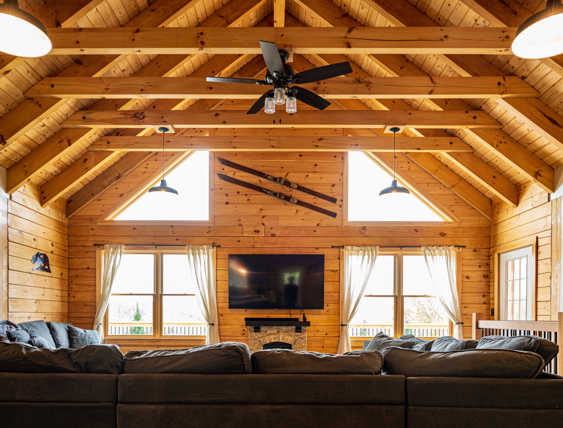 Sunapee great room with soaring cathedral ceiling, exposed beams, and gable-end windows