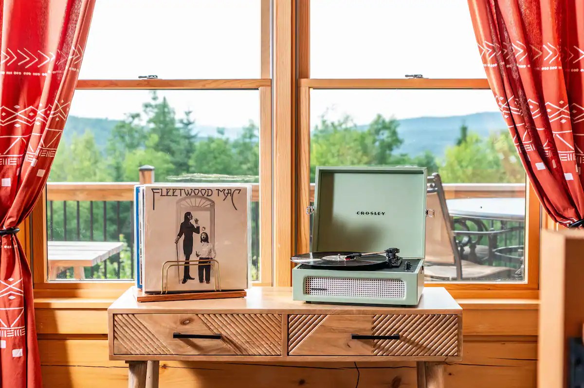 Crosley record player with vinyl records on a Sunapee window with view to the mountains