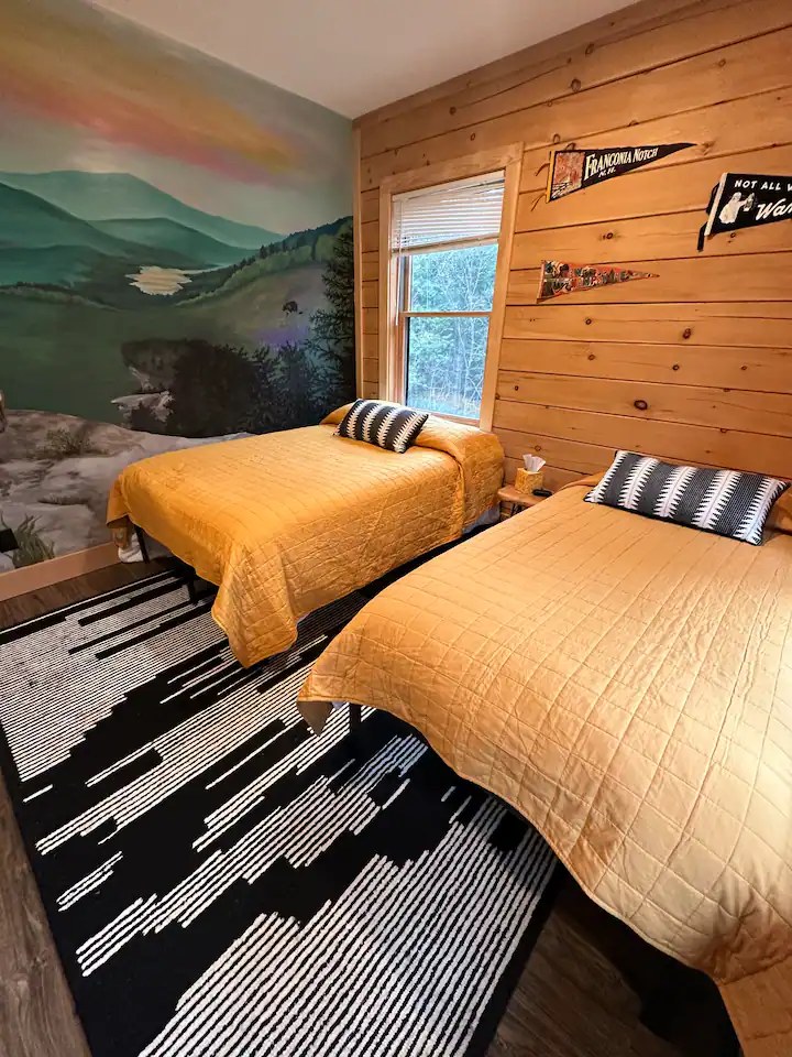 Second bedroom in the Sunapee with twin beds, mountain mural wall, and Franconia Notch pennant