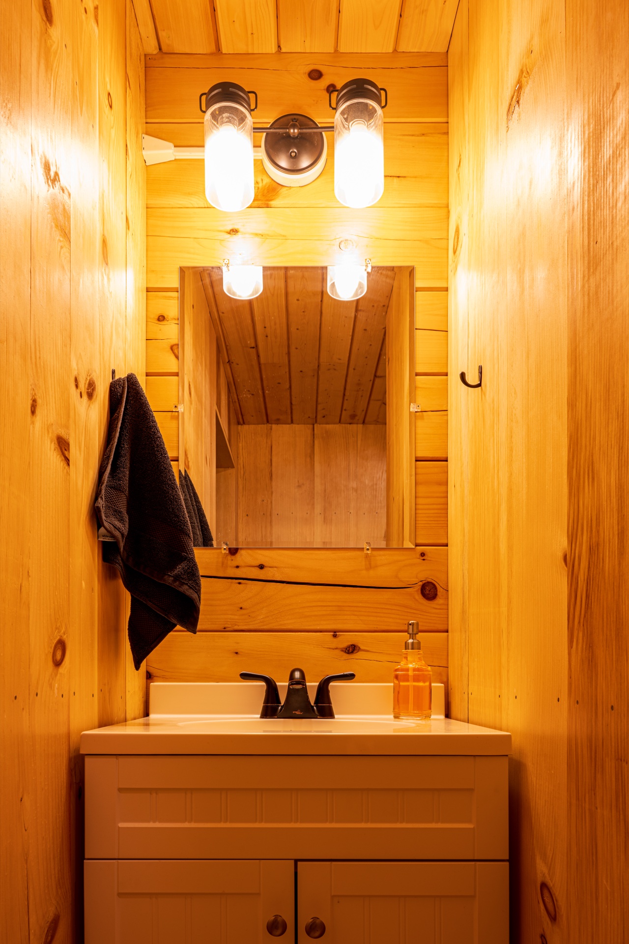 Tiny log home bathroom vanity with sconce lights and white sink