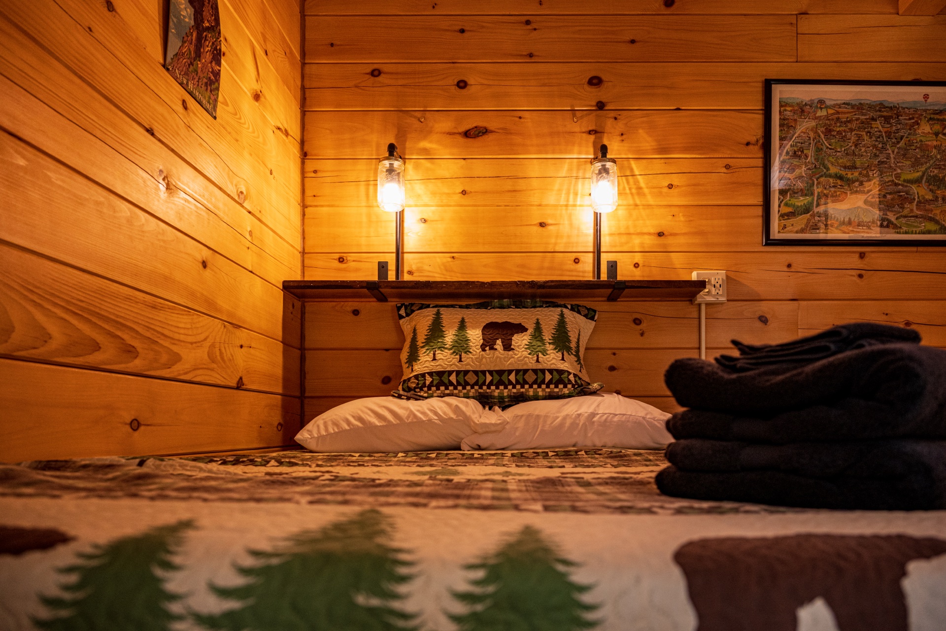 Tiny log home bedroom detail with bear pillow and double sconces