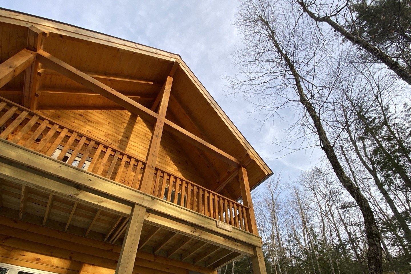 The Pine Springs tiny log home covered upper deck balcony with timber framing