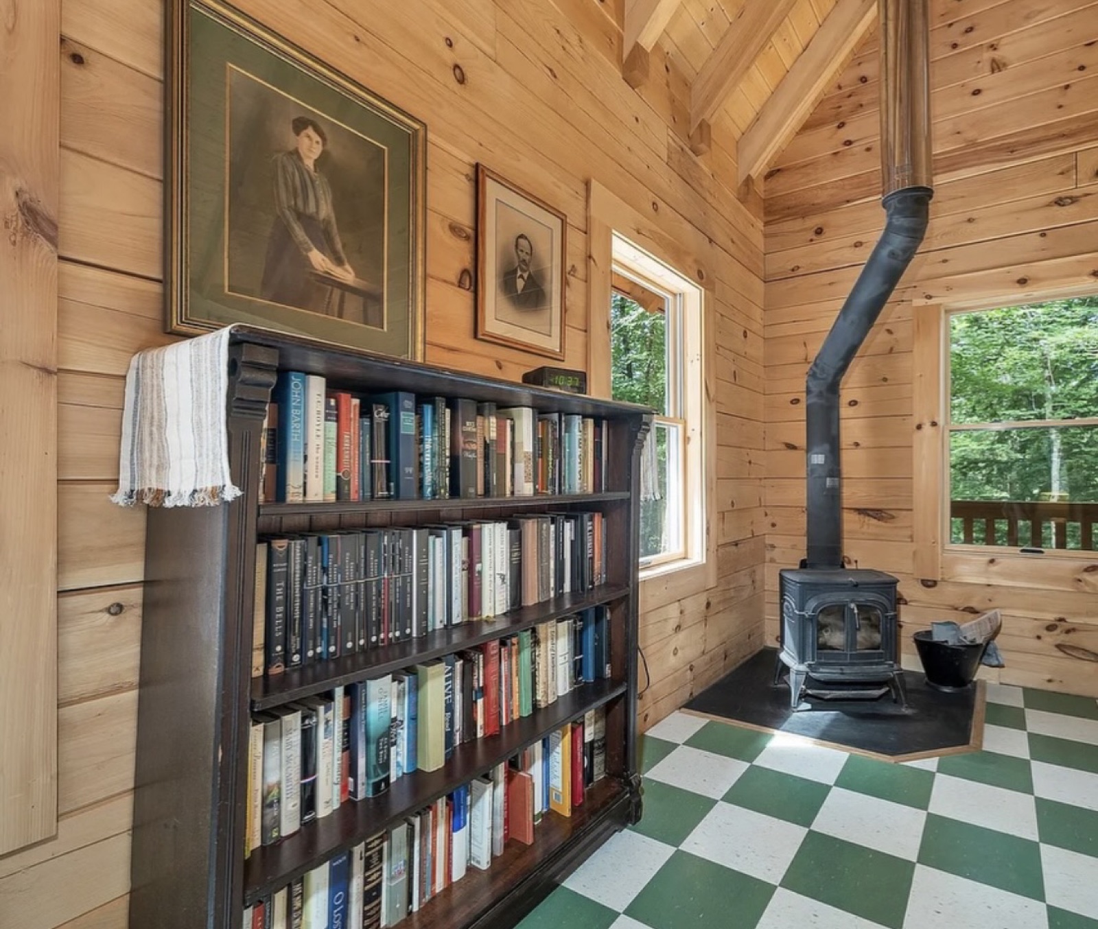 A reading nook inside the Pine Springs tiny log home with a bookshelf and a cast-iron wood stove