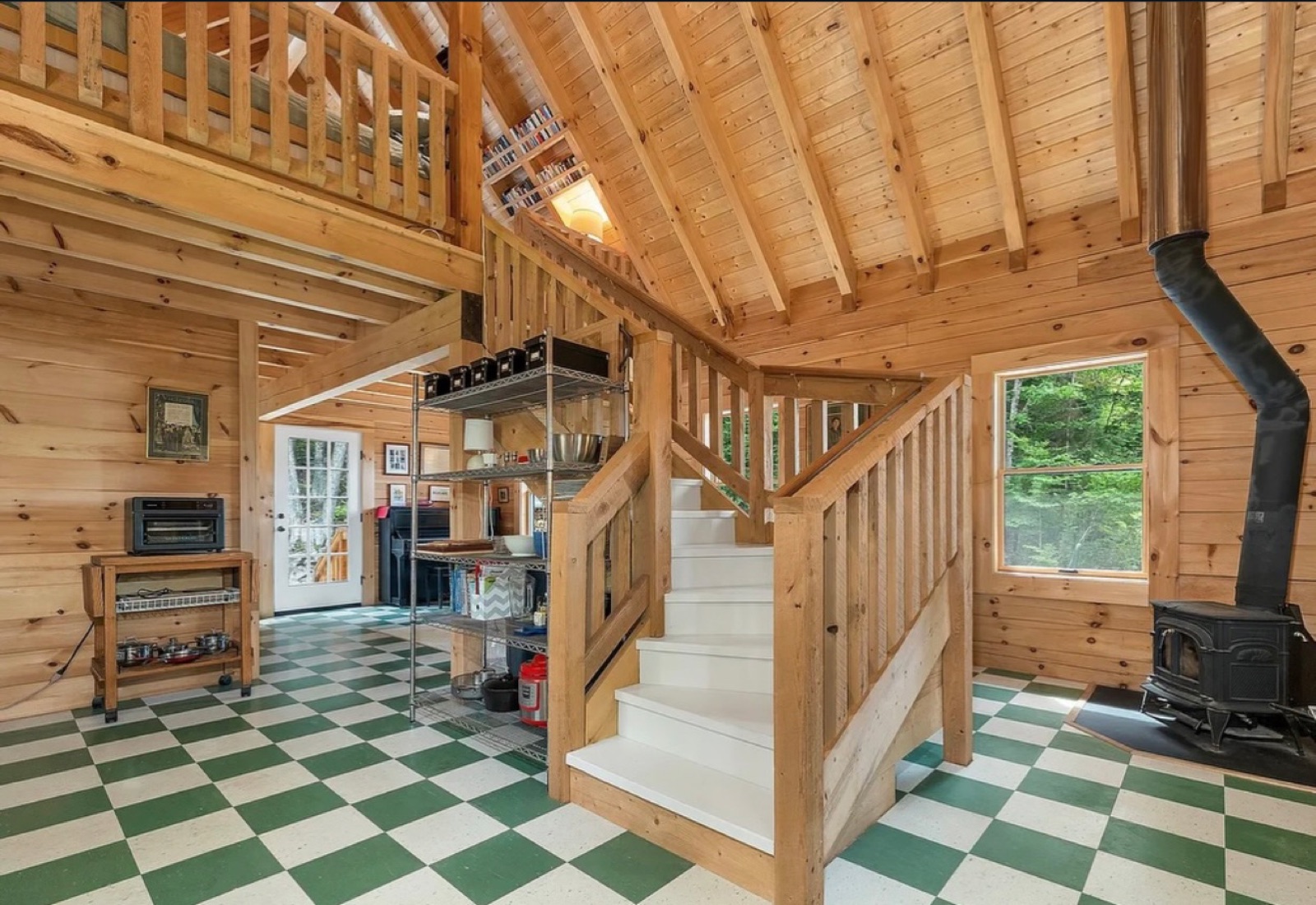 Inside the Pine Springs tiny log home showing the staircase, wood stove, and pine walls and ceiling
