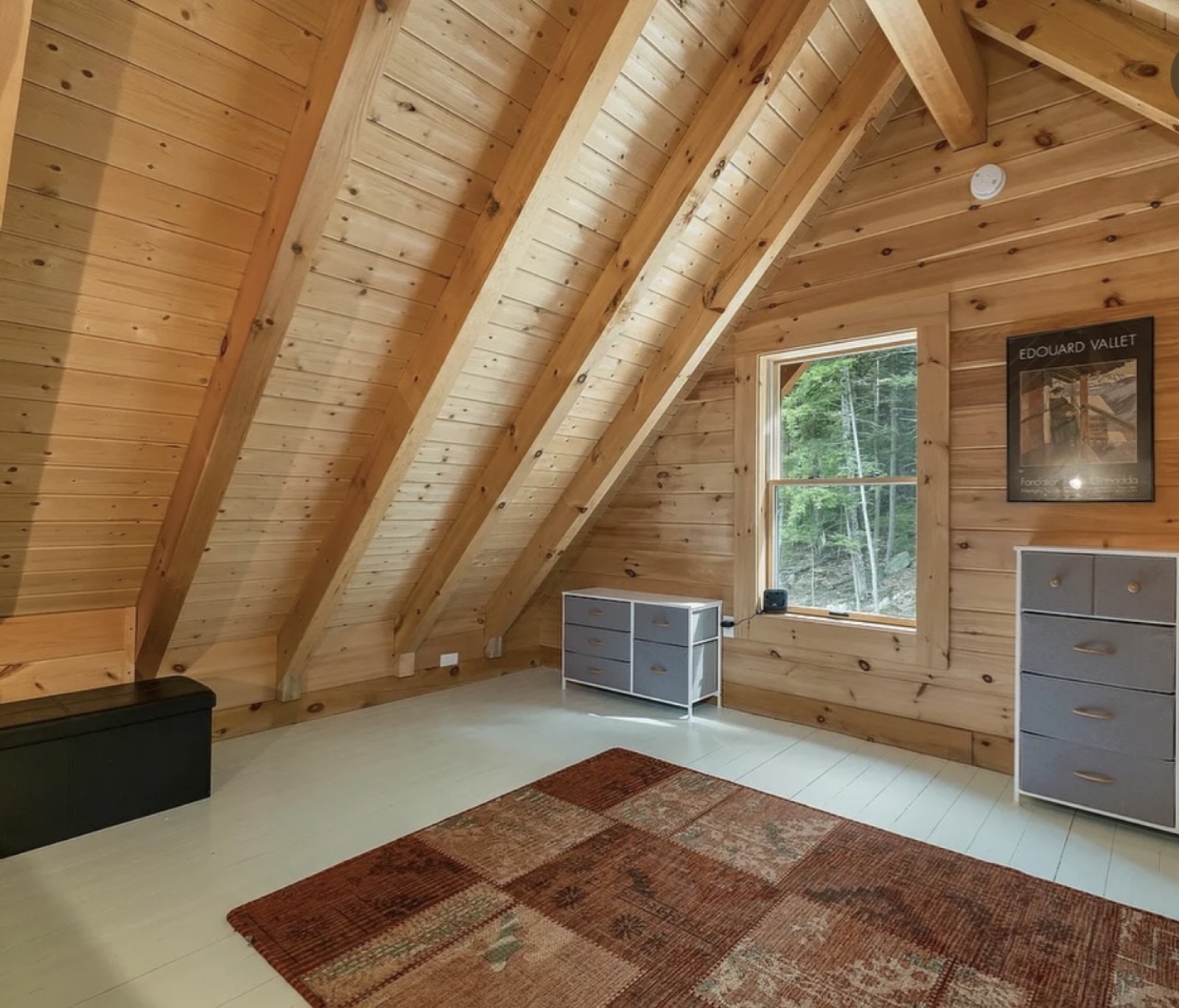 The vaulted pine loft inside the Pine Springs tiny log home with exposed rafters